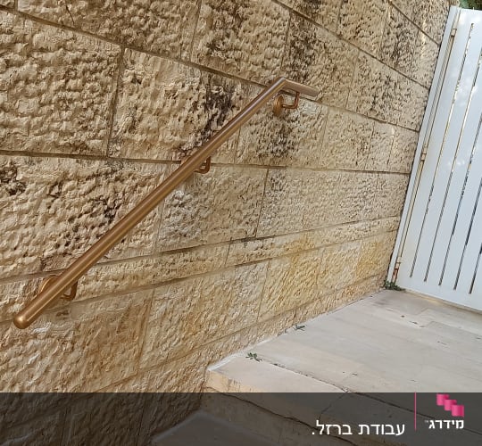 מעקה מתכת על קיר אבן ליד שער לבן